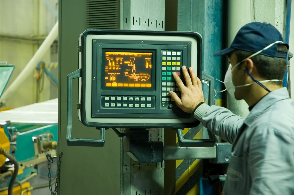 A worker touches a computer screen at a factory